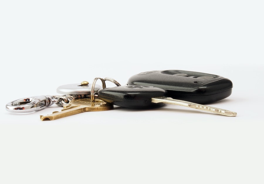 Car keys laying on white counter, the set includes a transponder key and a remote key.