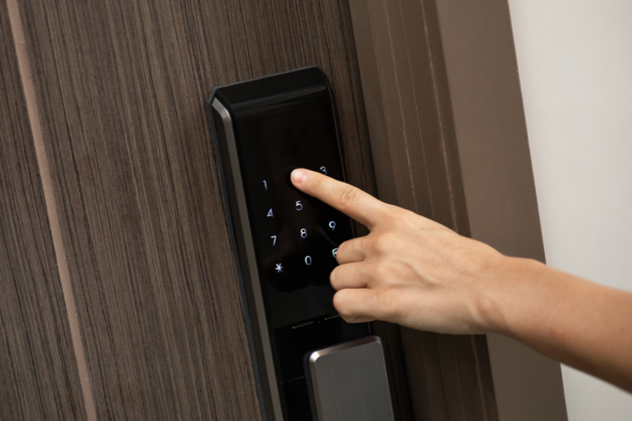 Image of a finger pressing buttons on a door security access pad.