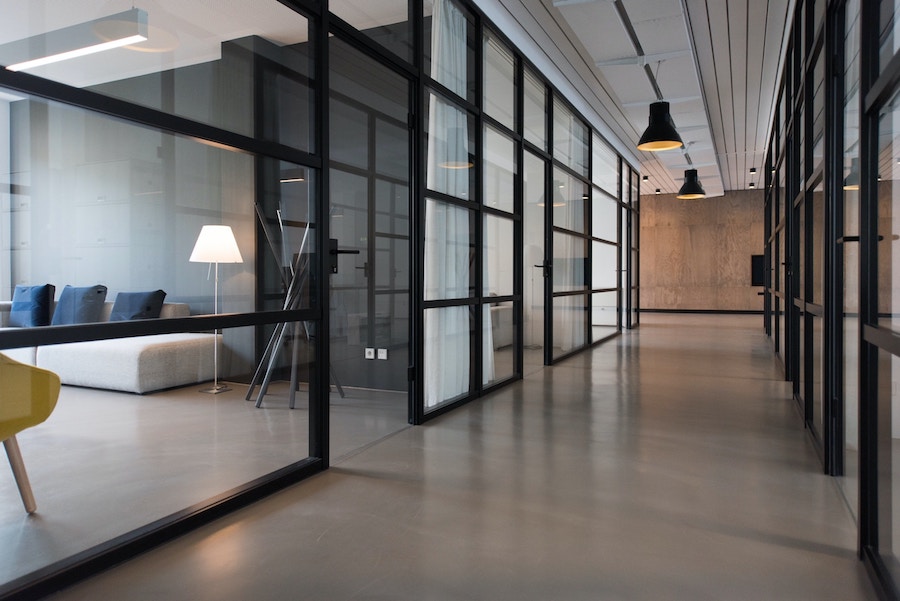 Corporate office hallway with meeting rooms featuring sliding glass doors.