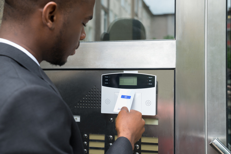 A man in a business suit using an access card on a secure entry system at a modern building entrance