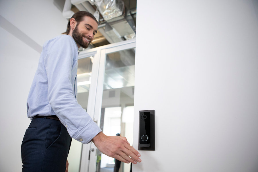 A man waving his hand in front of a wall-mounted Openpath access control device.