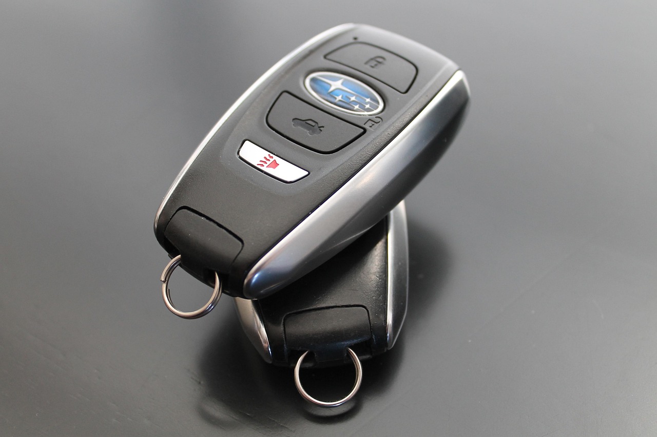 Subaru key fob with lock, trunk release, and panic buttons resting on a smooth black surface.