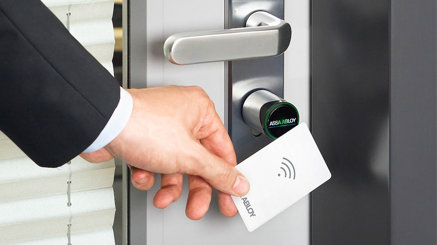 A man uses a keycard to open a door protected by a commercial lever/lock set.