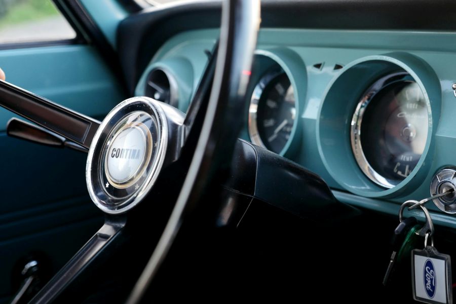 A set of car keys in the ignition of a vehicle with a teal dashboard.