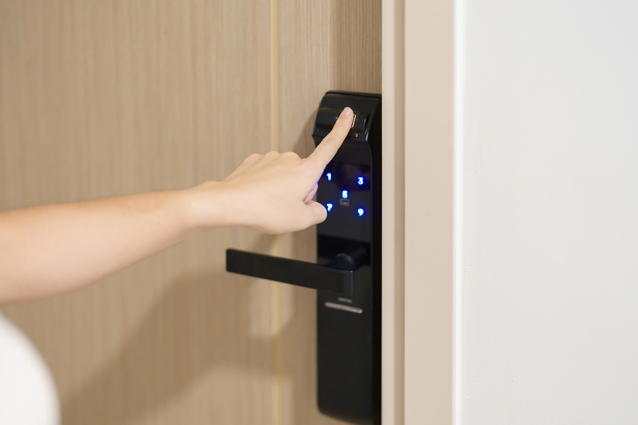 Closeup of a hand aiming for buttons on a smart lock installed on a business door.